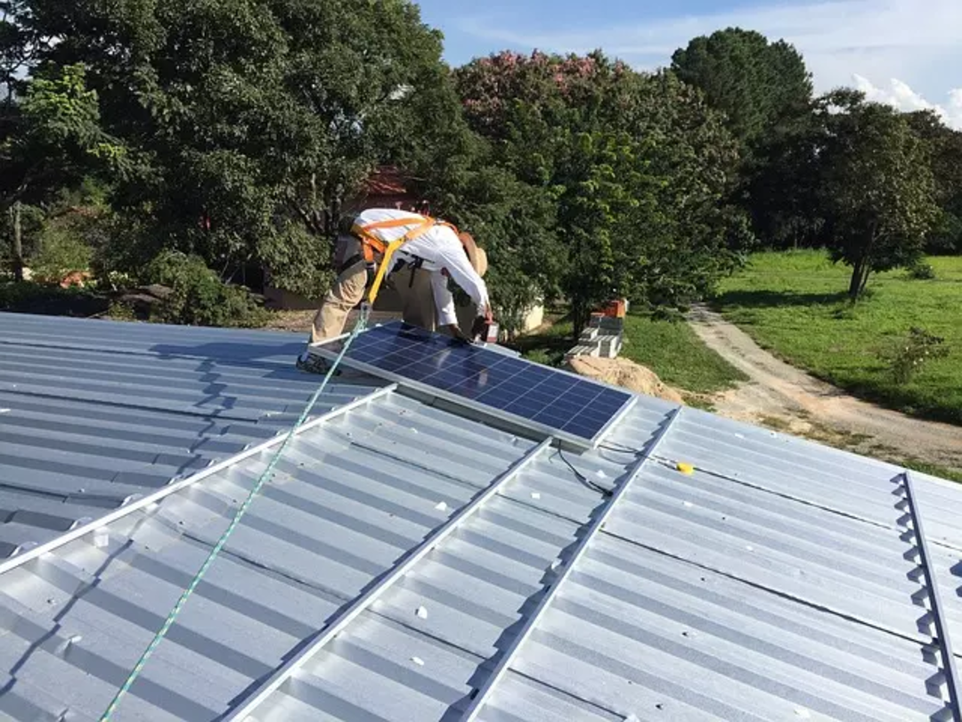 fachowiec montuje panele fotowoltaiczne na dachu